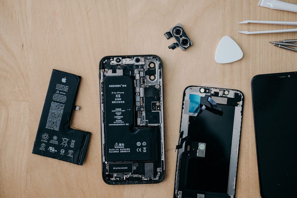 Opengewerkte smartphone met losse onderdelen en gereedschap op een werkbank