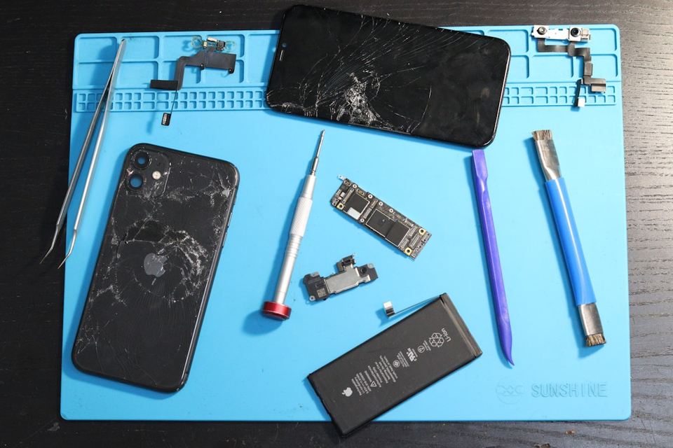 Gebarsten telefoonscherm en gereedschap op een blauwe reparatiemat