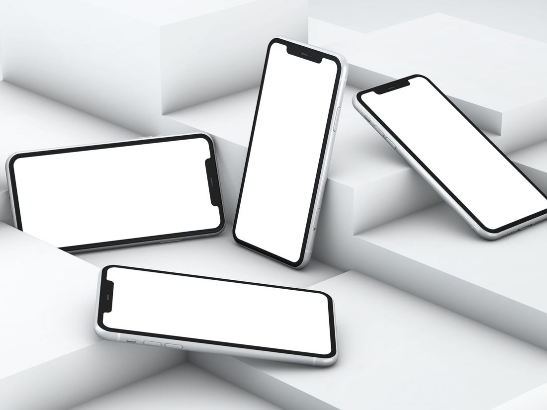 Vier witte smartphones opgesteld op lichte blokken